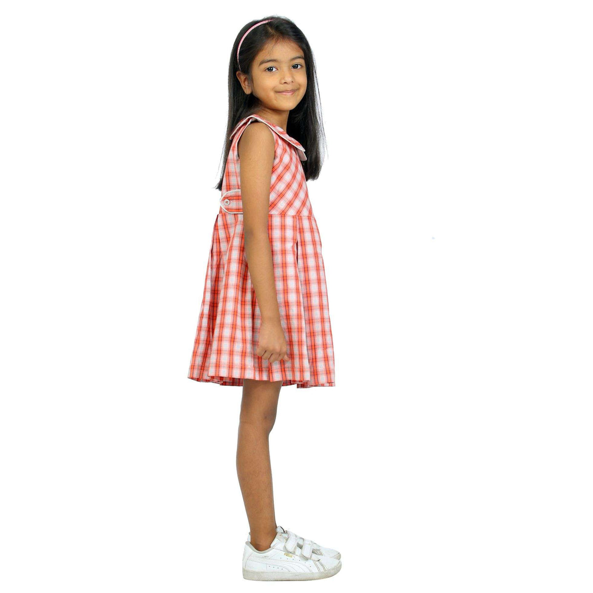 Side angle shot of a girl wearing red plaid sleeveless dress