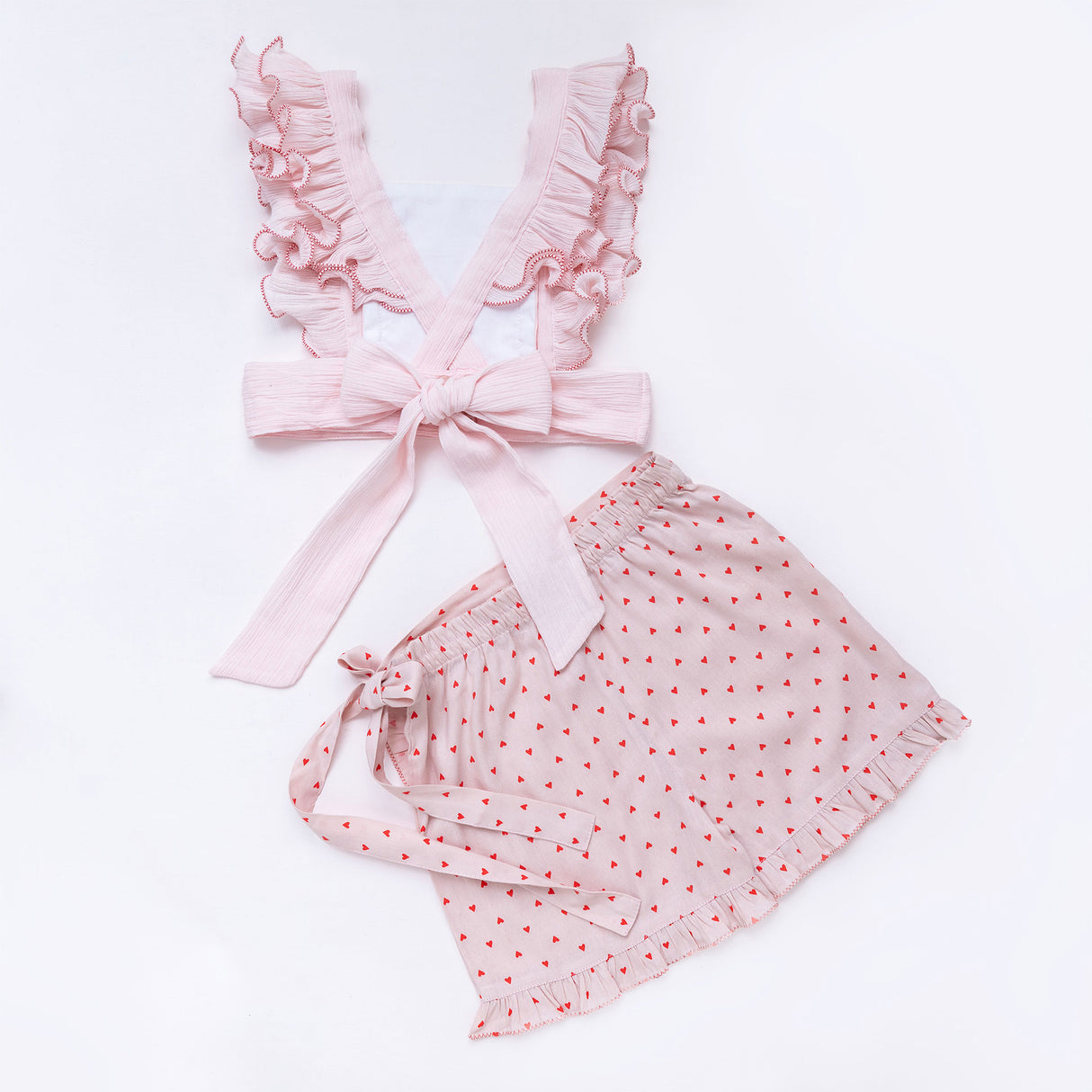 Flatlay of the rear side of hand embroidered blouse with criss cross ruffled straps and ruffled hem skort set