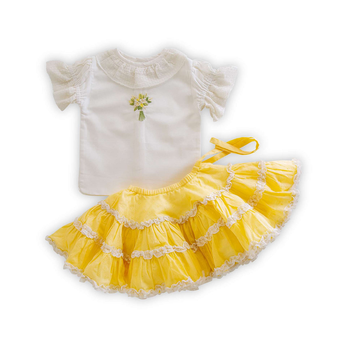 Flatlay of yellow layered flared skirt paired with white blouse with gathered sleeves, ruffled collar and hand embroidered design on front