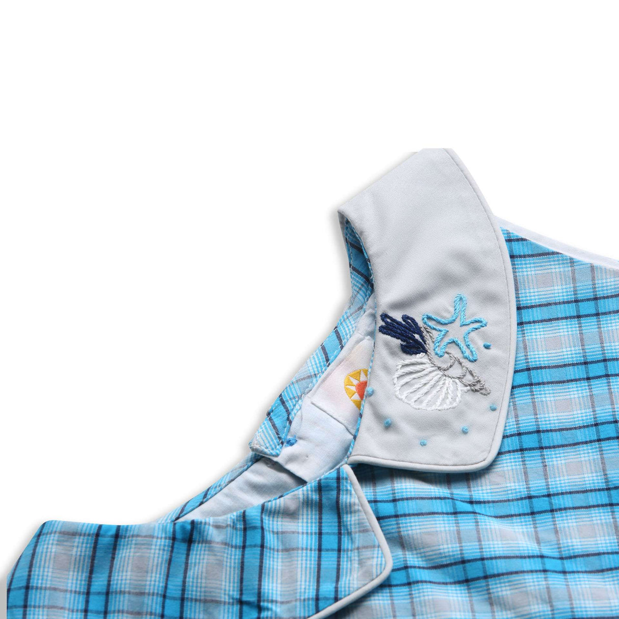 Close up of bright blue plaid dress with box pleated skirt and hand embroidered design on grey collar