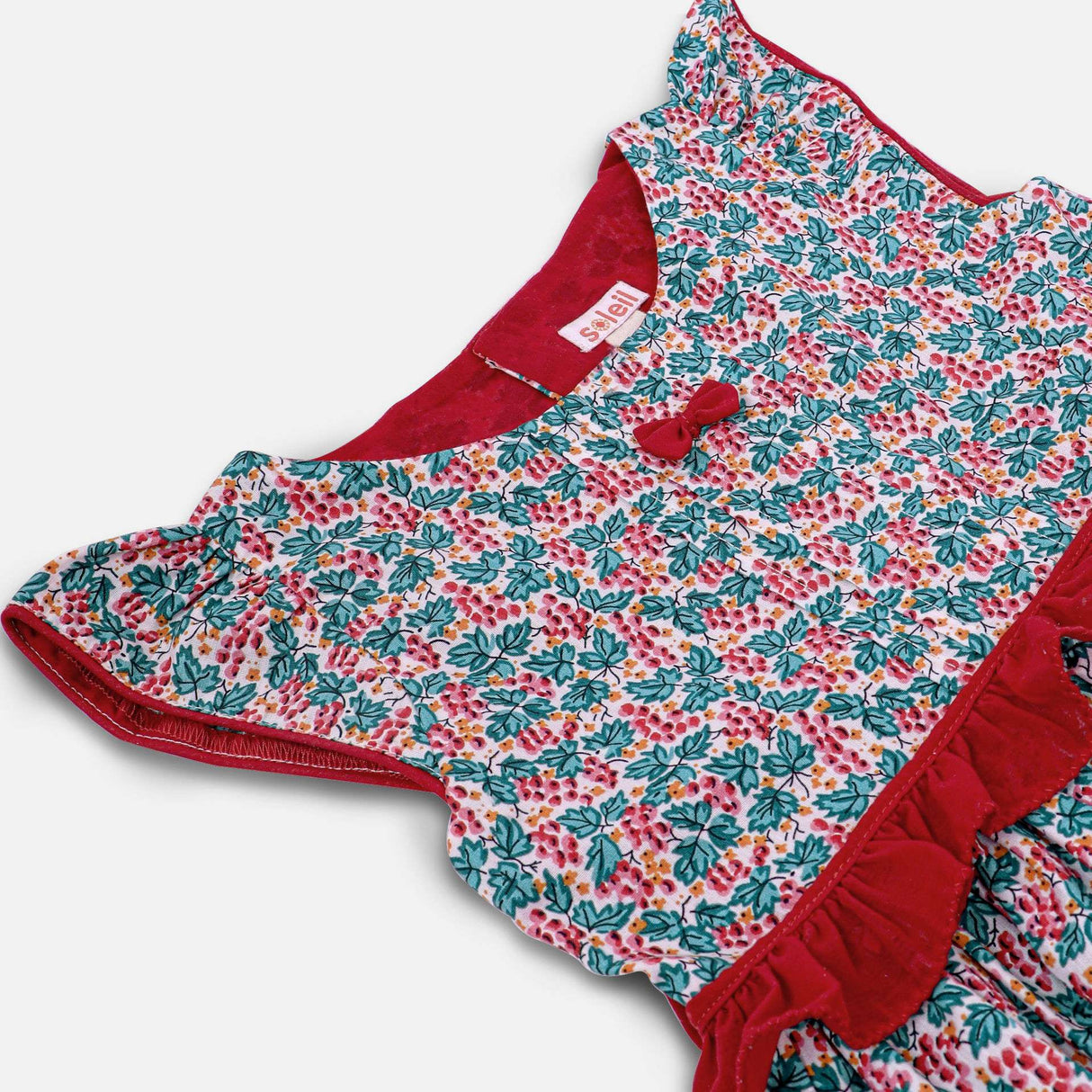 Flatlay of red and green floral printed cotton dress with a tie up fabric ruffle belt