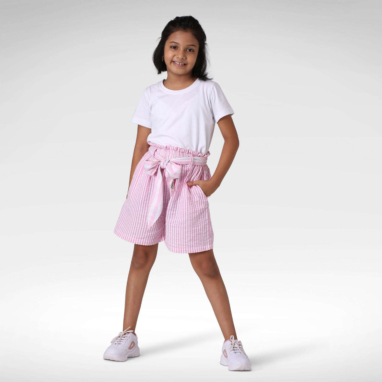 A girl in a white tee and pink striped shorts with a reversible fabric belt