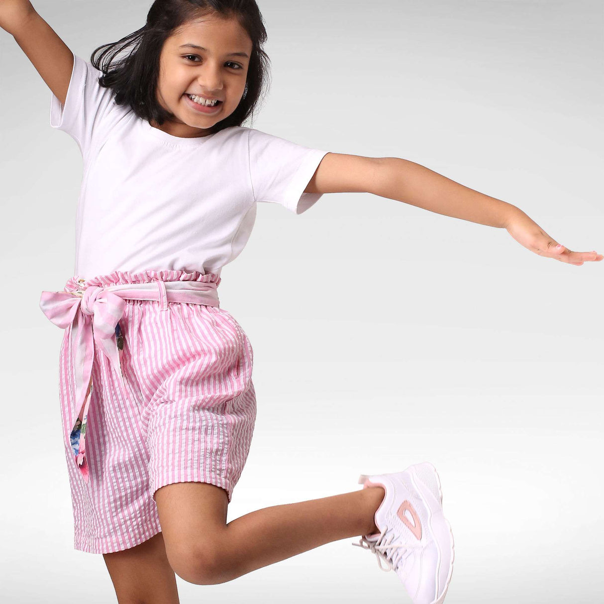 A little girl in pink striped paper bag shorts with removable fabric belt
