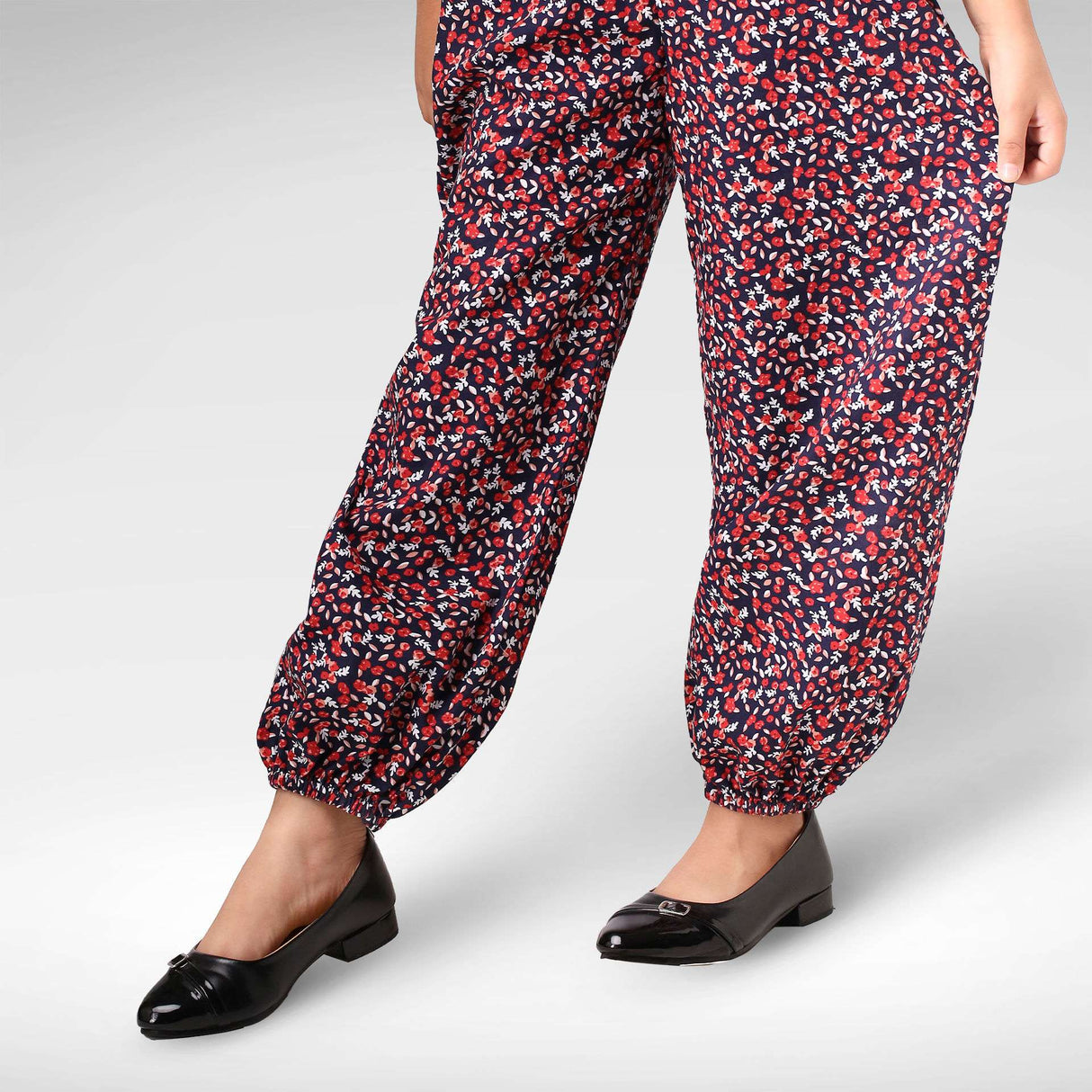 Close-up of a girl in a black and red floral printed jumpsuit with cinched cuffs at the ankle