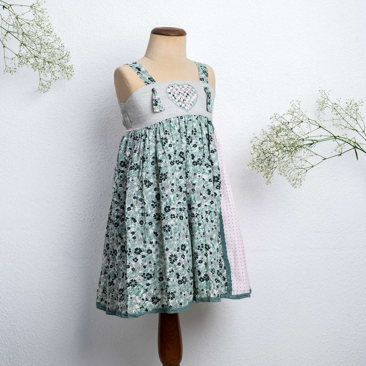 Mannequin image of strappy dress with floral print and pink dot fabric with intricate ribbon patchwork heart applique