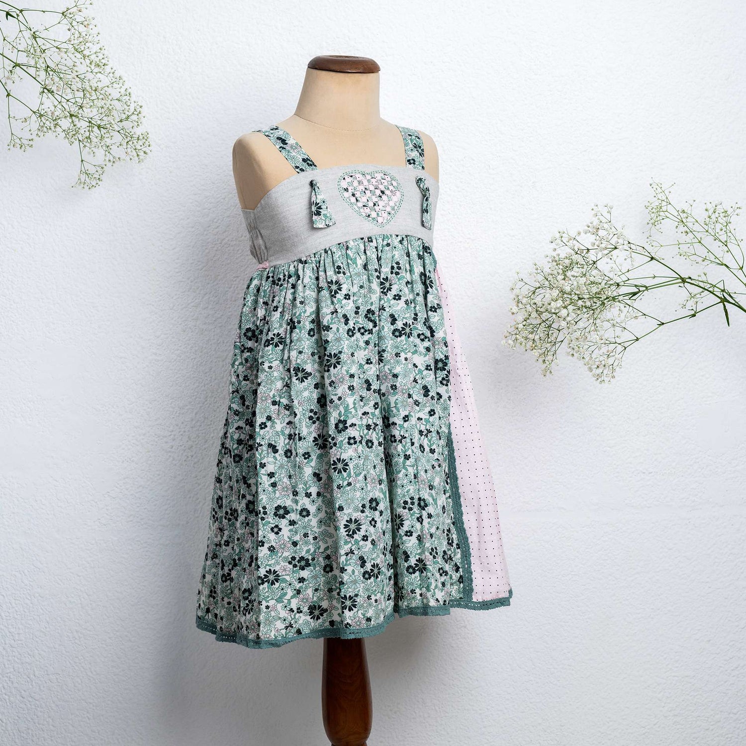 Mannequin image of strappy dress with floral print and pink dot fabric with intricate ribbon patchwork heart applique