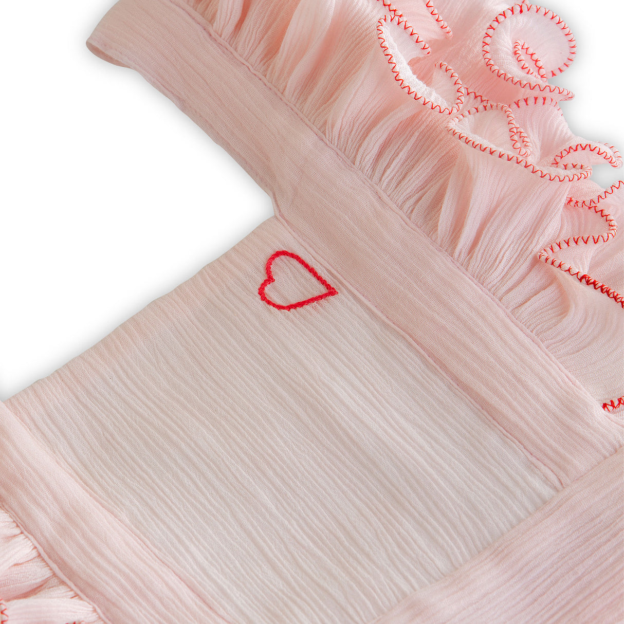 Close-up of strappy tie-up blouse with hand embroidered red heart and ruffled criss cross straps