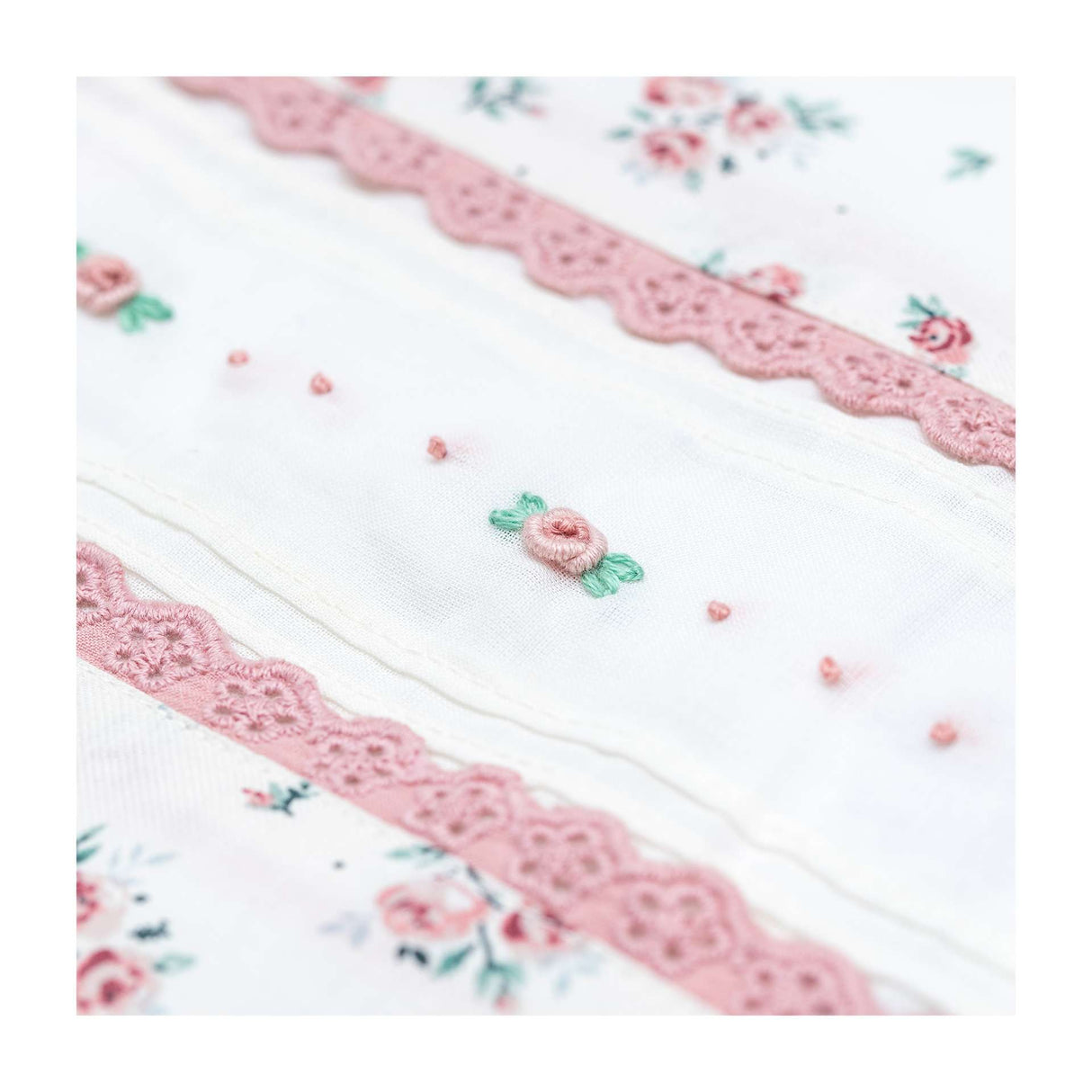 Close-up of the hand embroidered pleated bodice of ivory floral-spray printed dress with lace trims
