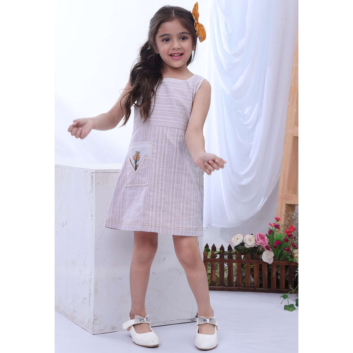 Girl posing in sleeveless A-line dress with a hand embroidered motif on the pocket