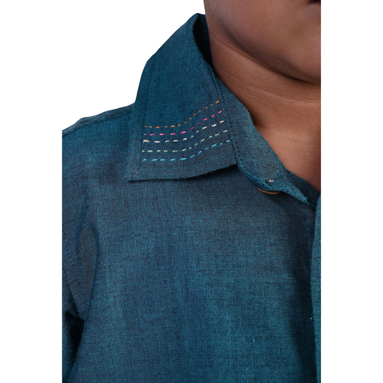 Close up of a boy wearing a teal chambray shirt- the collar has hand embroidery detailing