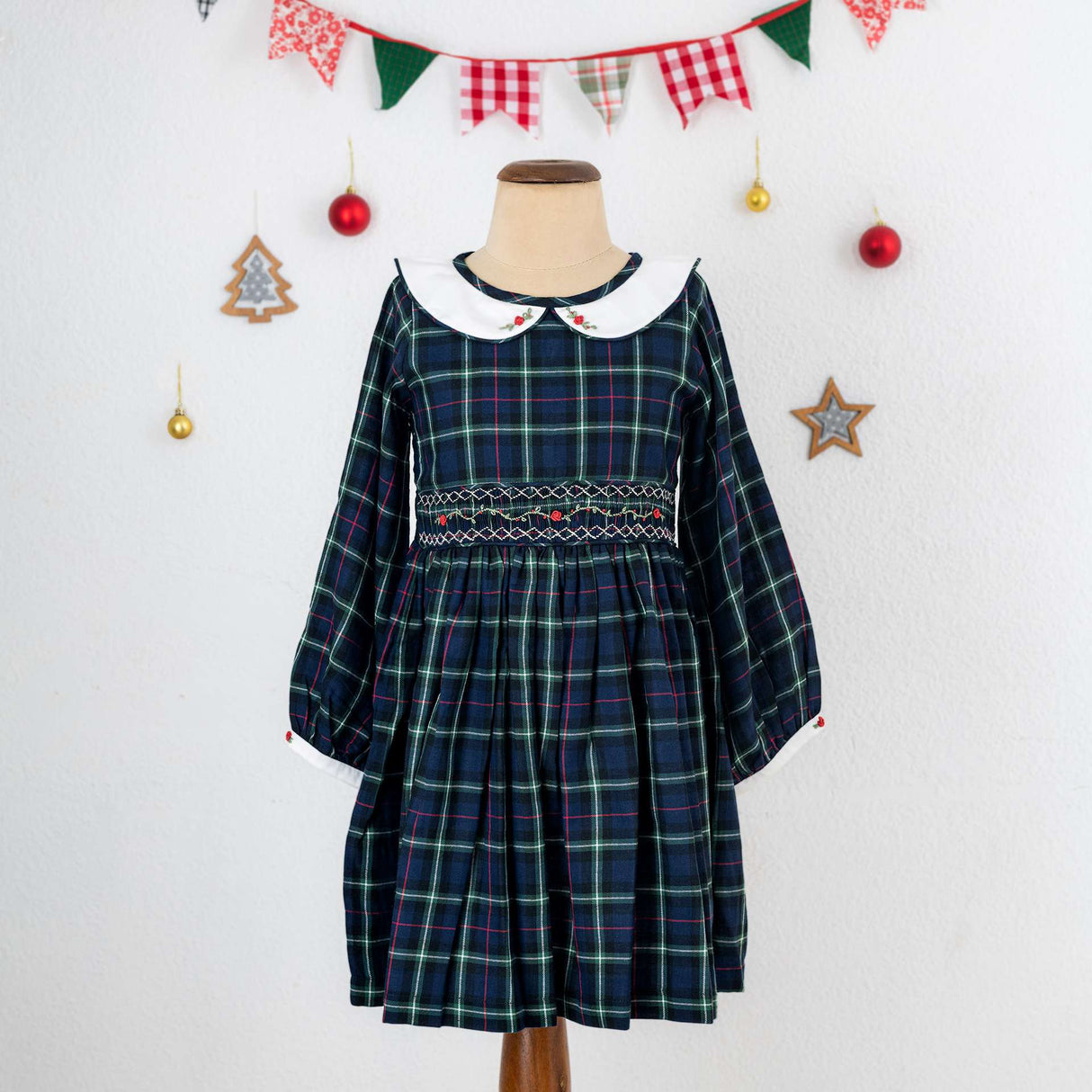 A little girl in navy plaid hand smocked cotton dress with hand embroidered collar