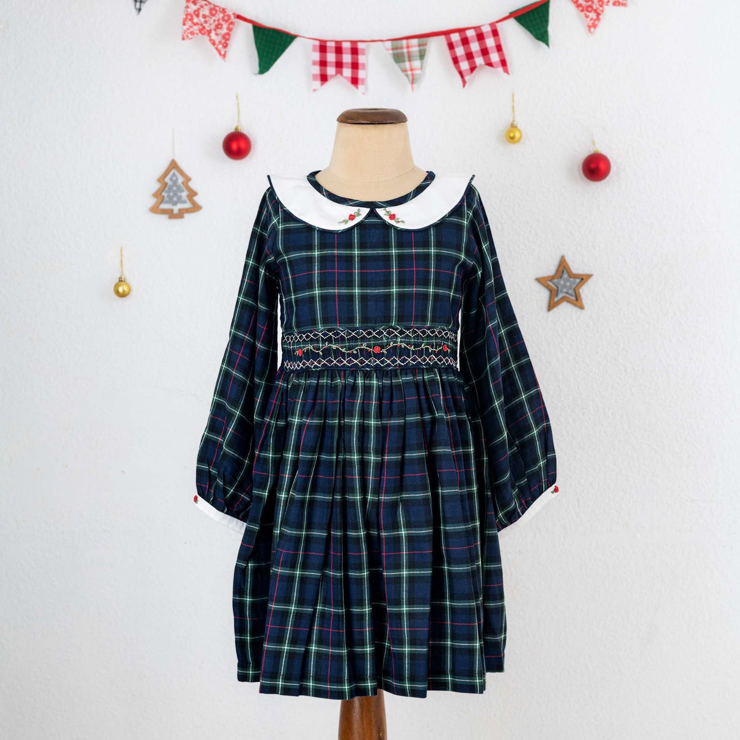 A little girl in navy plaid hand smocked cotton dress with hand embroidered collar