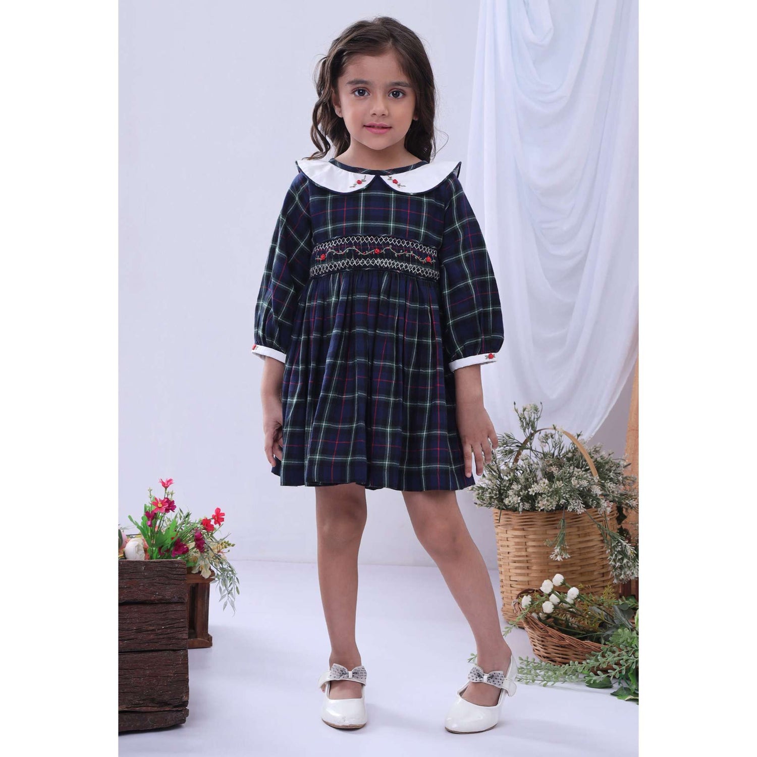 A little girl in navy plaid hand smocked cotton dress with hand embroidered collar