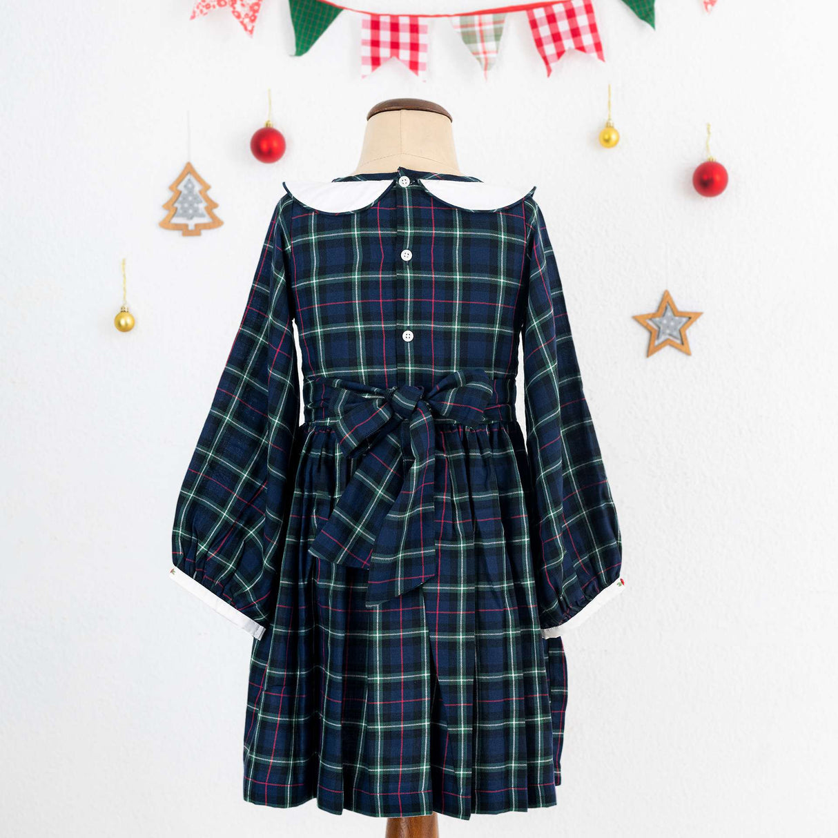 A little girl in navy plaid hand smocked cotton dress with hand embroidered collar
