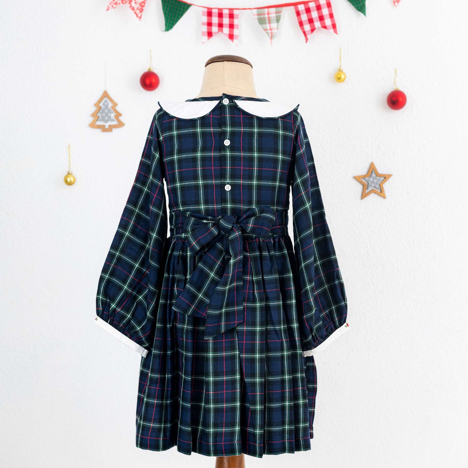 A little girl in navy plaid hand smocked cotton dress with hand embroidered collar