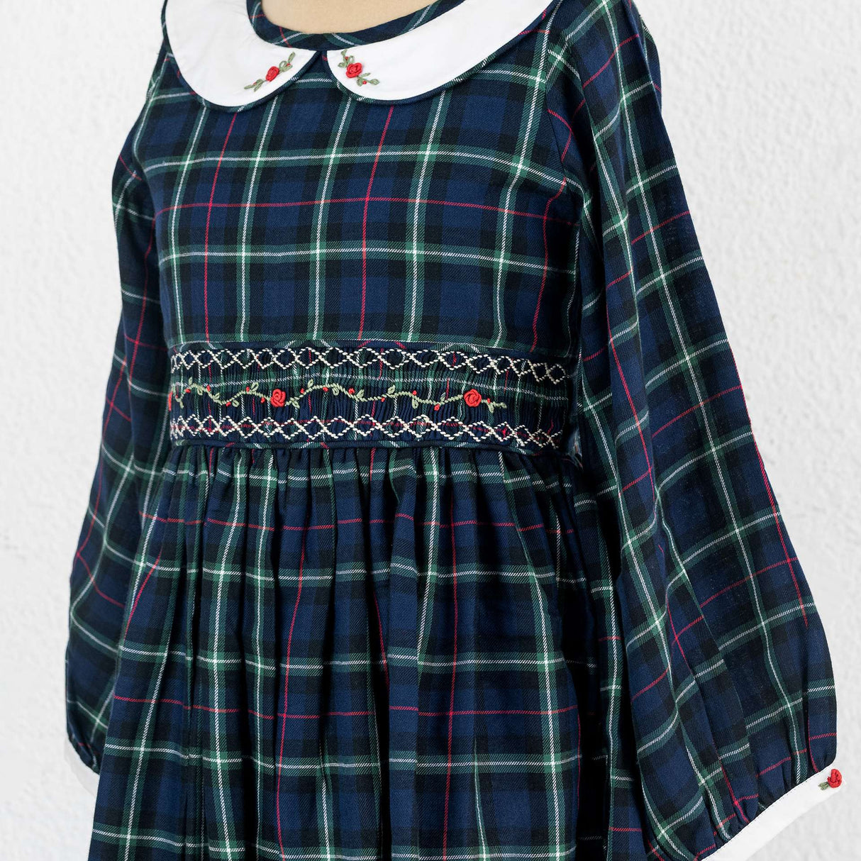 A little girl in navy plaid hand smocked cotton dress with hand embroidered collar