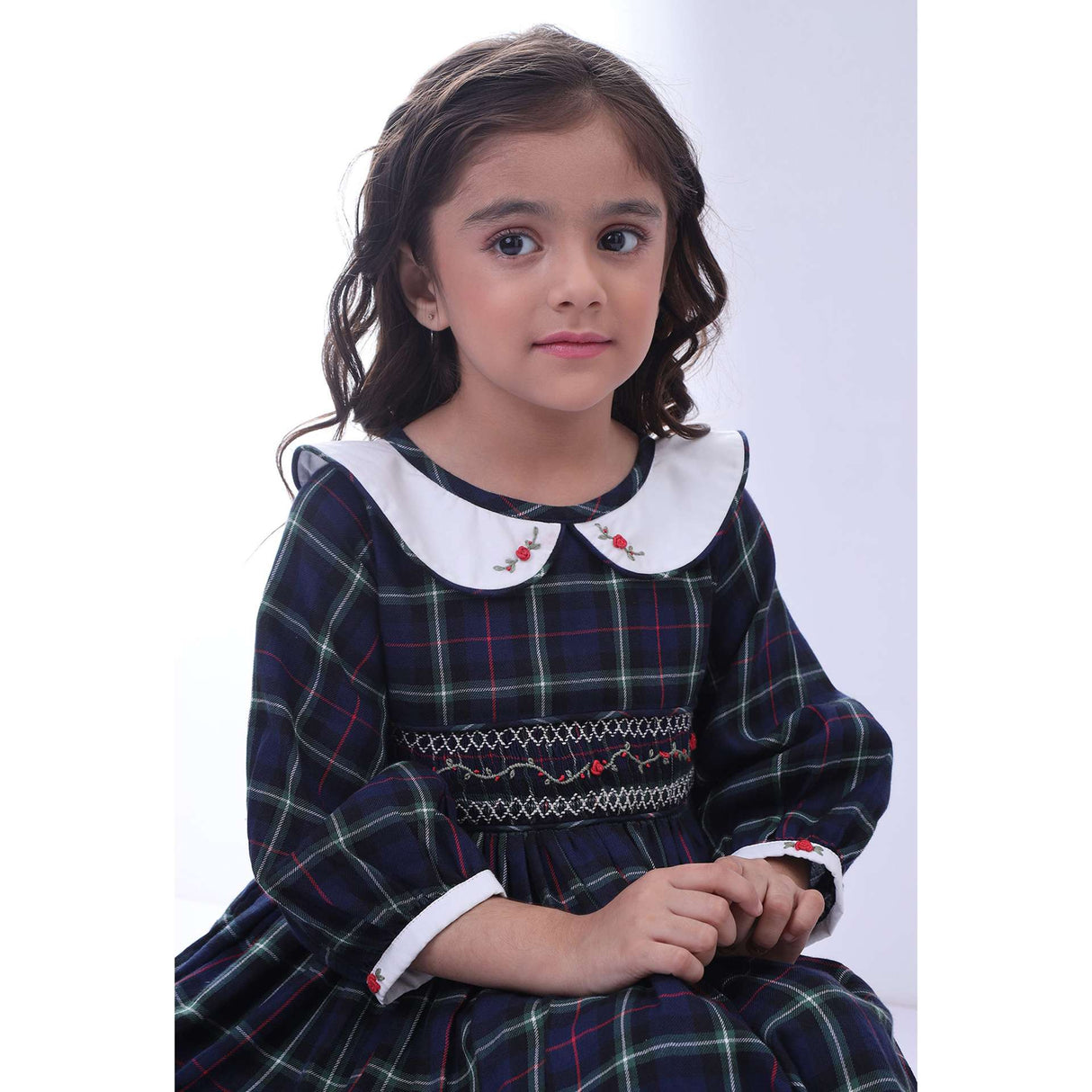 A little girl in navy plaid hand smocked cotton dress with hand embroidered collar
