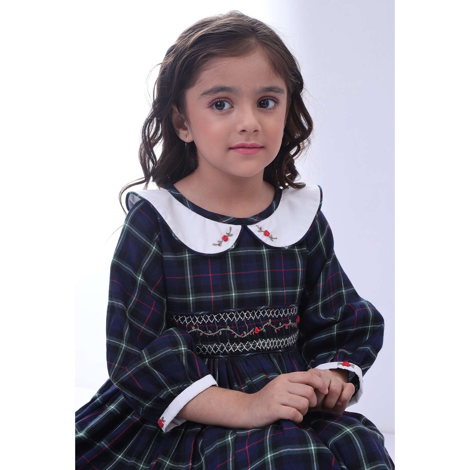 A little girl in navy plaid hand smocked cotton dress with hand embroidered collar