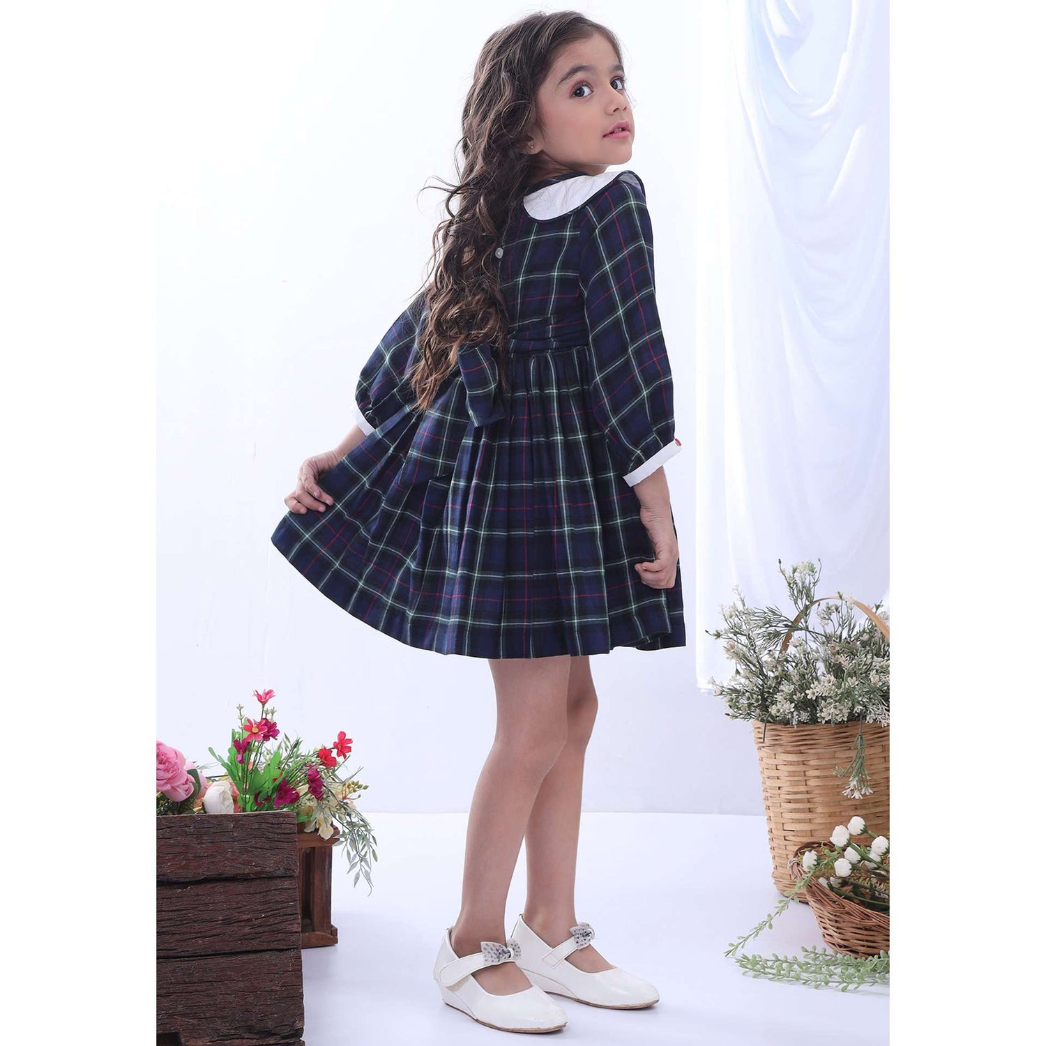 A little girl in navy plaid hand smocked cotton dress with hand embroidered collar