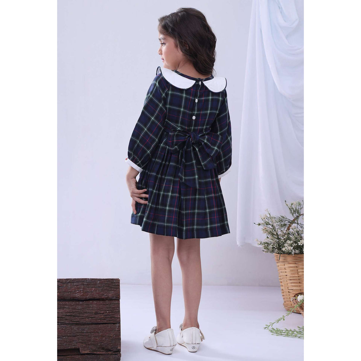 A little girl in navy plaid hand smocked cotton dress with hand embroidered collar