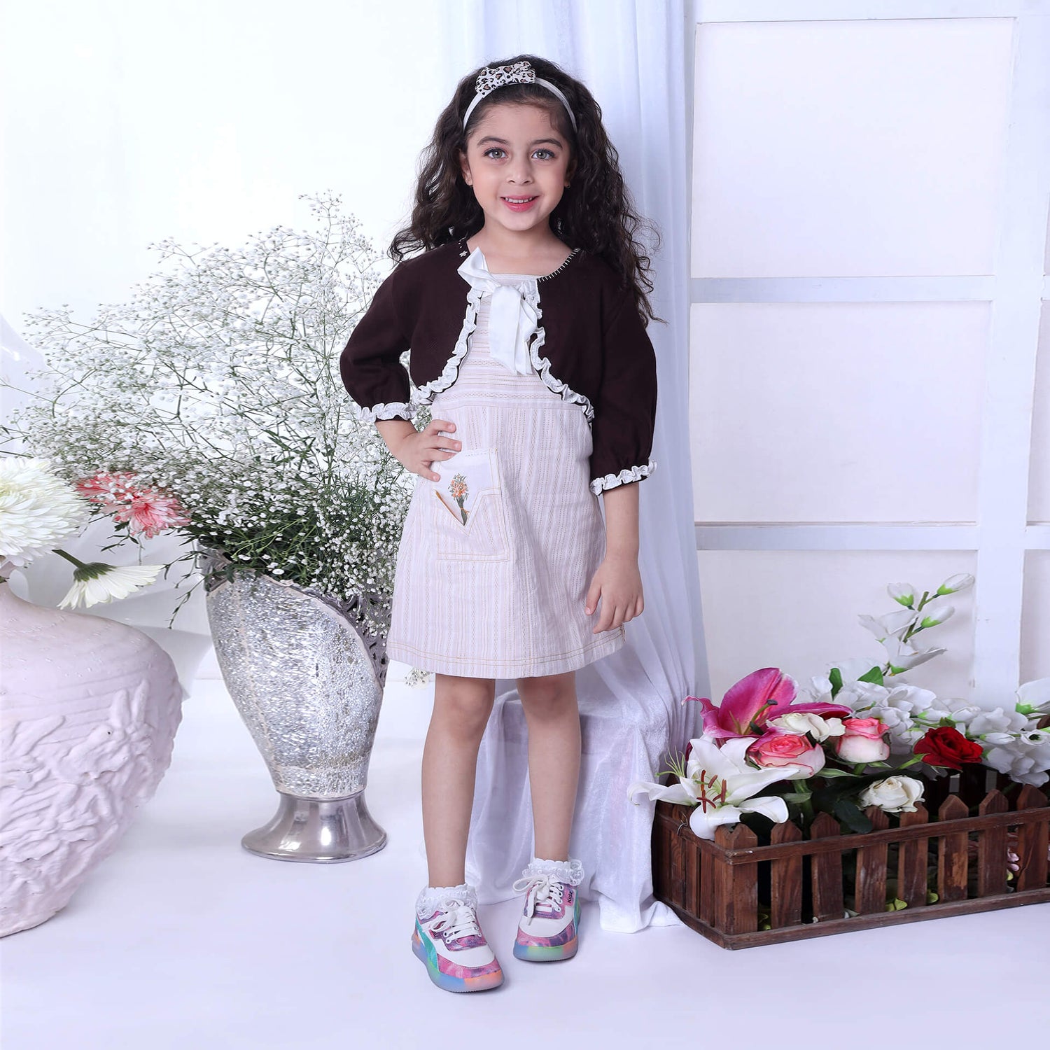A girl in a woolen bolero jacket featuring delicate white ruffles
