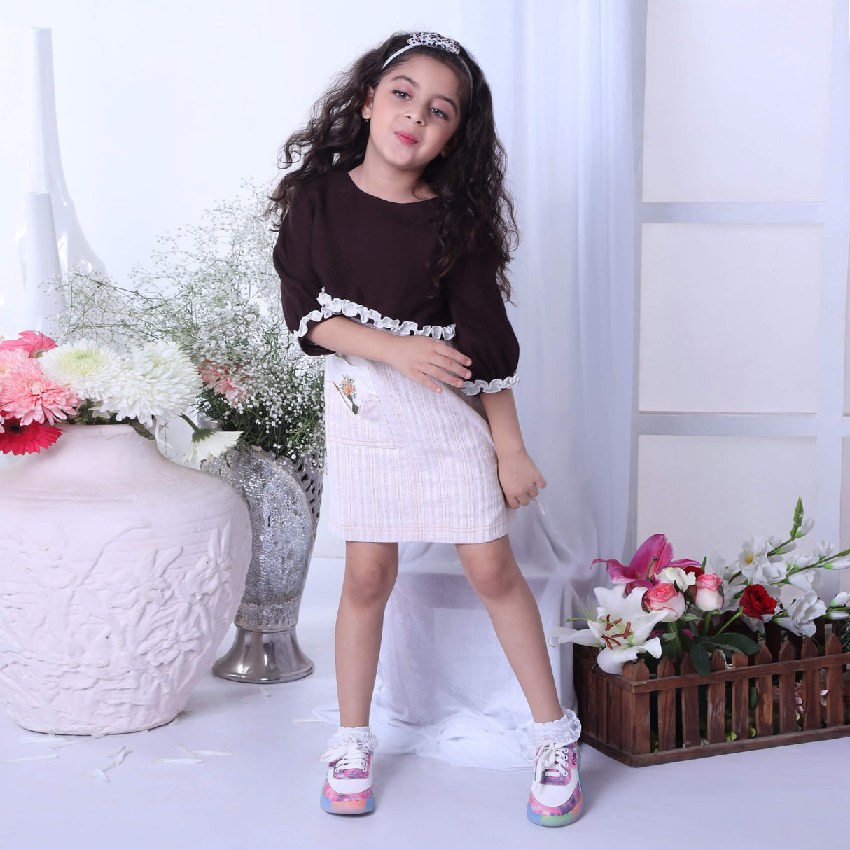 Dancing gracefully, a young girl in an ivory A-line dress paired with a brown bolero embroidered jacket