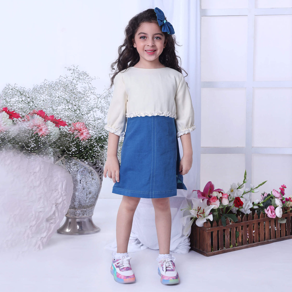Girl wears a blue A-line dress paired with an ivory bolero embroidered jacket with ruffle details