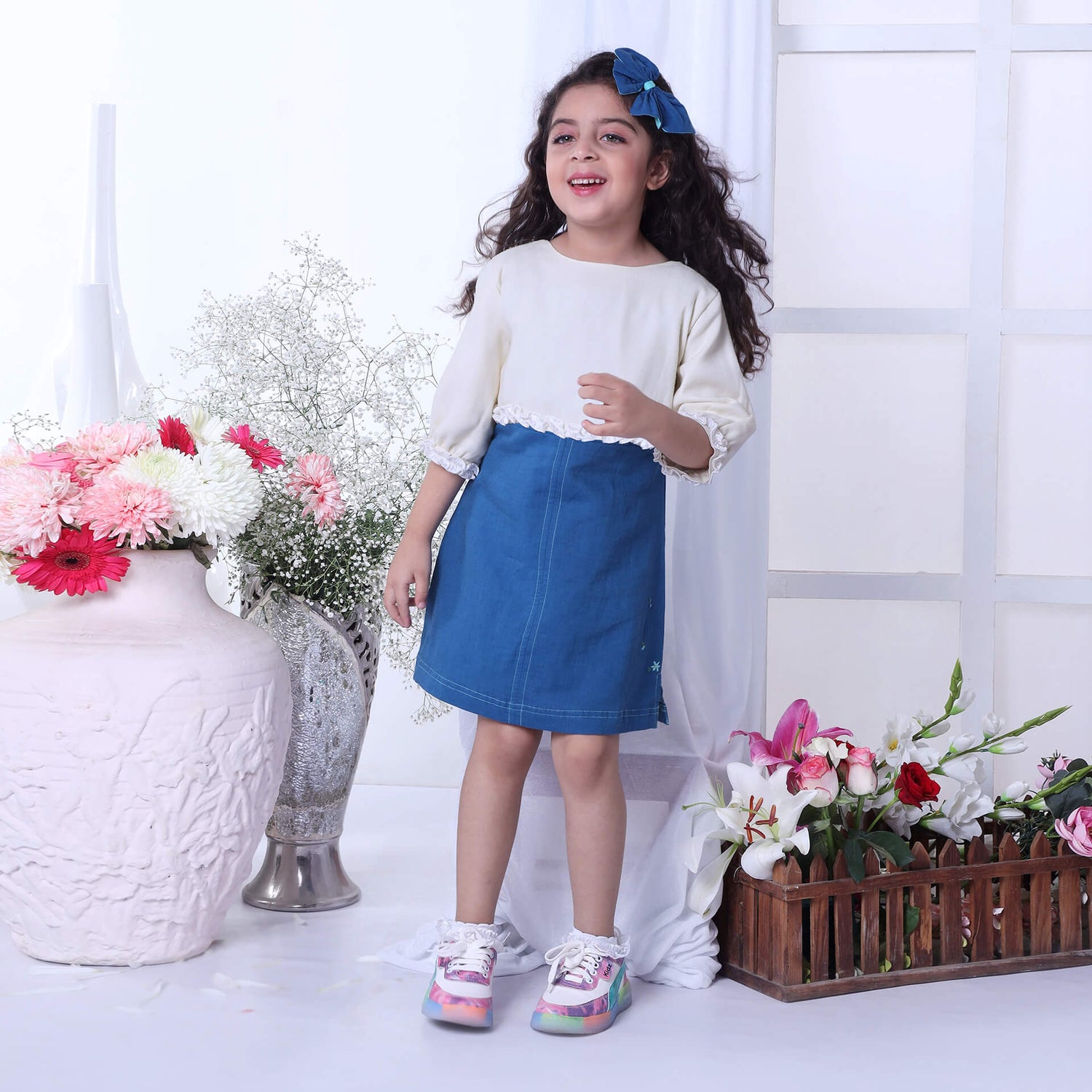 A girl wears a blue A-line dress paired with an ivory bolero embroidered jacket with ruffle details