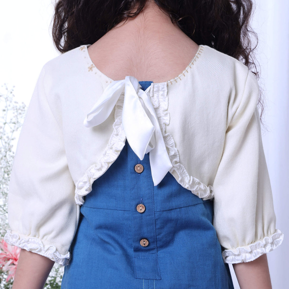 Back view of an embroidered ivory bolero jacket with tie up satin sash