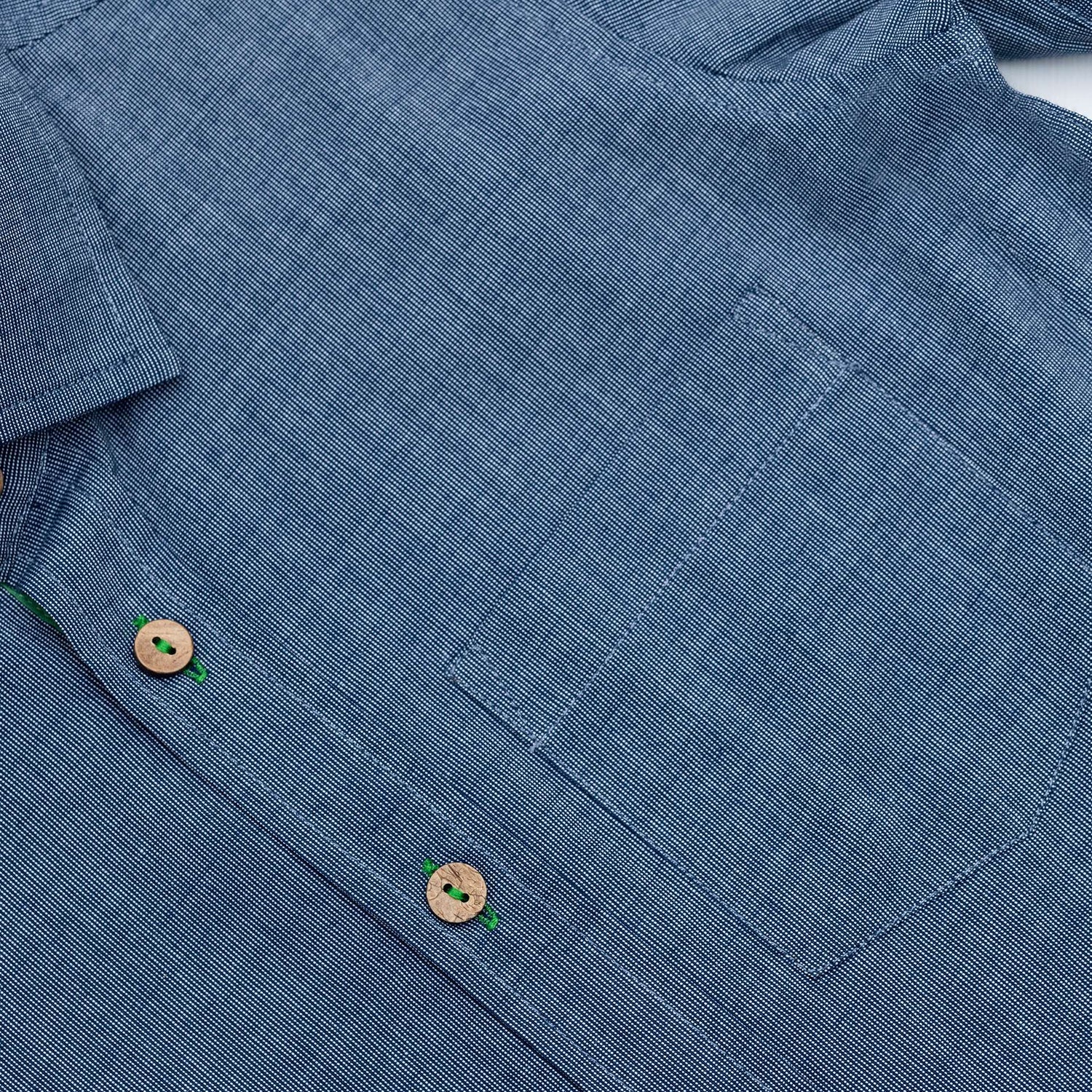 Close up of blue button down shirt with front pocket and wood buttons down the front