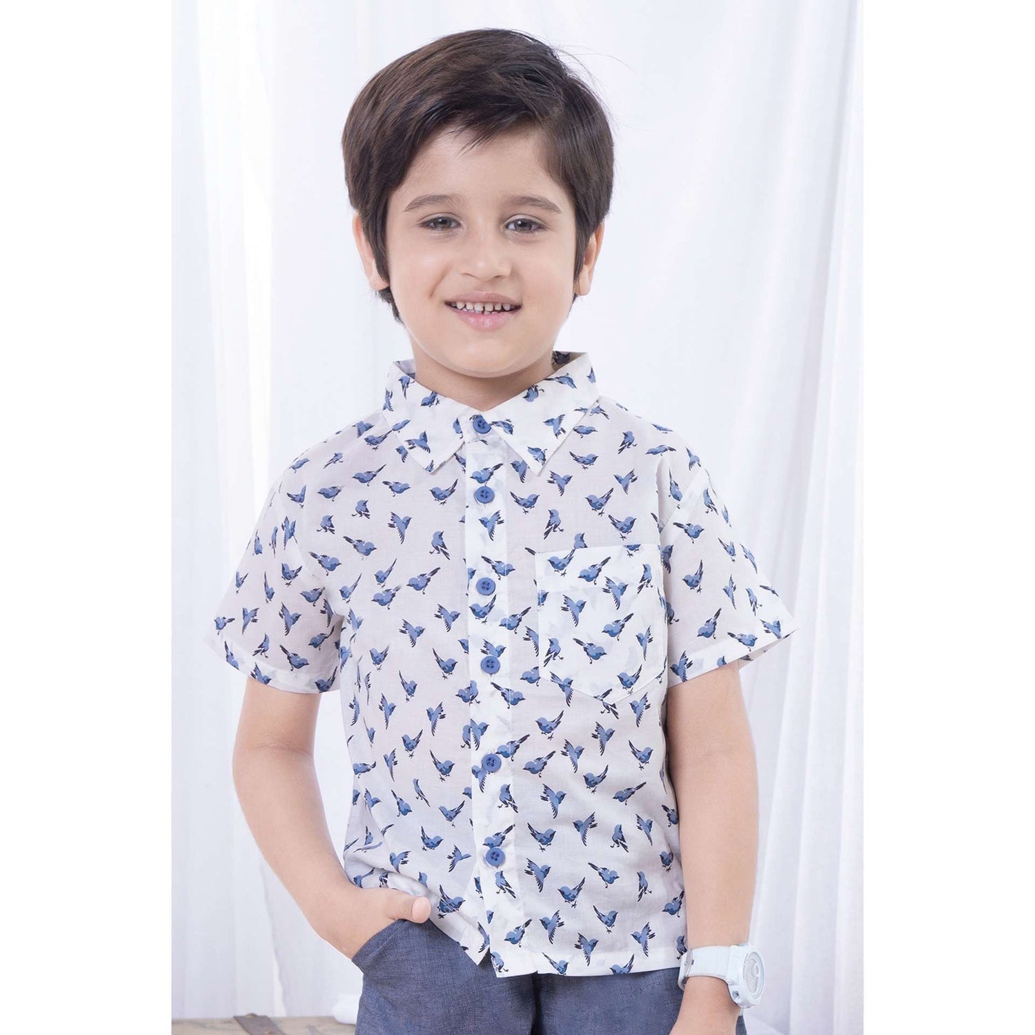 Boy wears a bird print half sleeve shirt and smiles