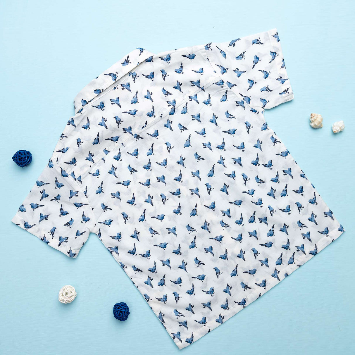 Back of a boys shirt with half sleeves in an ivory and blue bird print