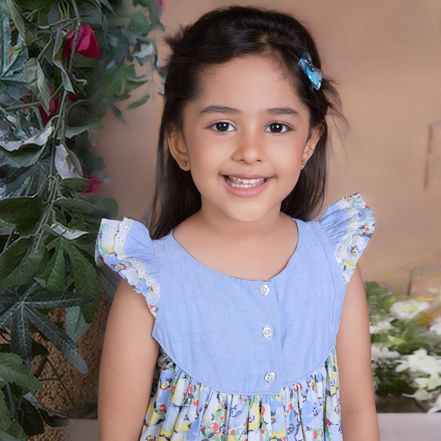 A little girl in blue chambray floral printed cotton dress with flutter sleeves, eyelet lace trims and ruffled hem