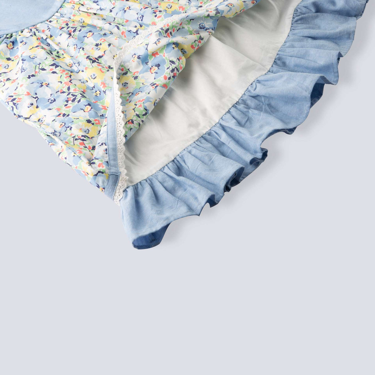 Close up of the ruffled hem in blue chambray floral printed cotton dress