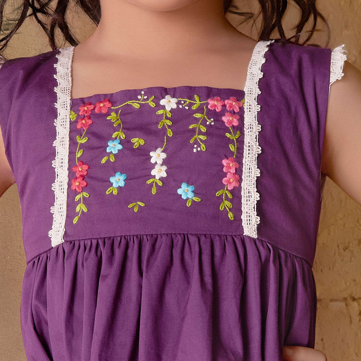 Close-up image of the yoke of magenta dress with hand embroidered floral garlands, embellished with woven lace