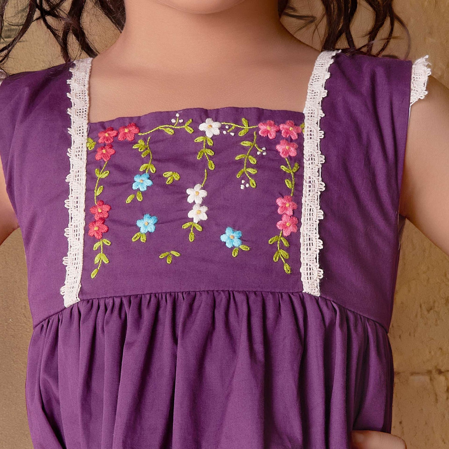 Close-up image of the yoke of magenta dress with hand embroidered floral garlands, embellished with woven lace