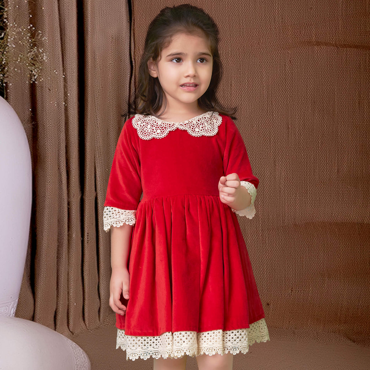 Cute girl in red velvet dress adorned with white lace