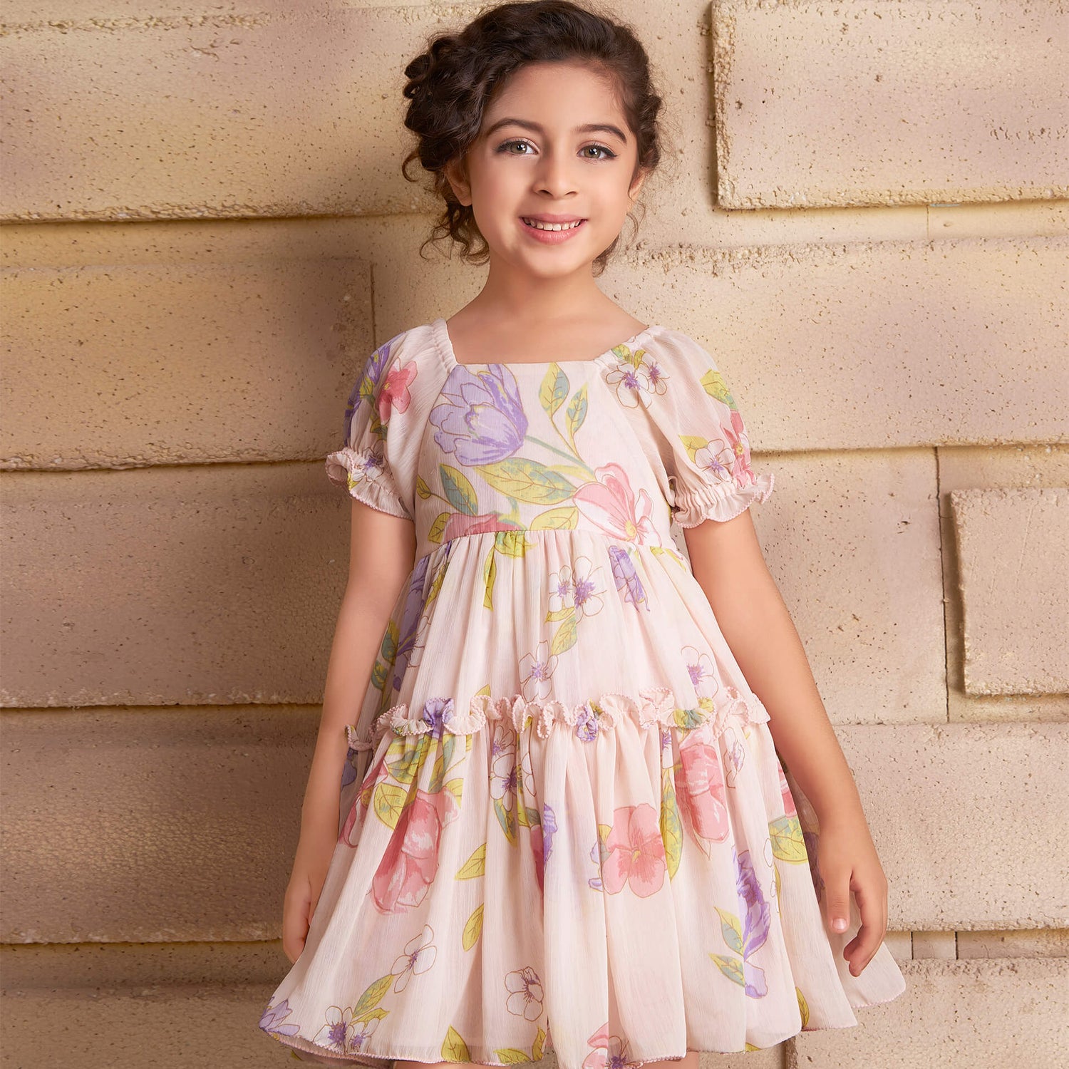 A smiling girl wearing a pink chiffon ruffle dress