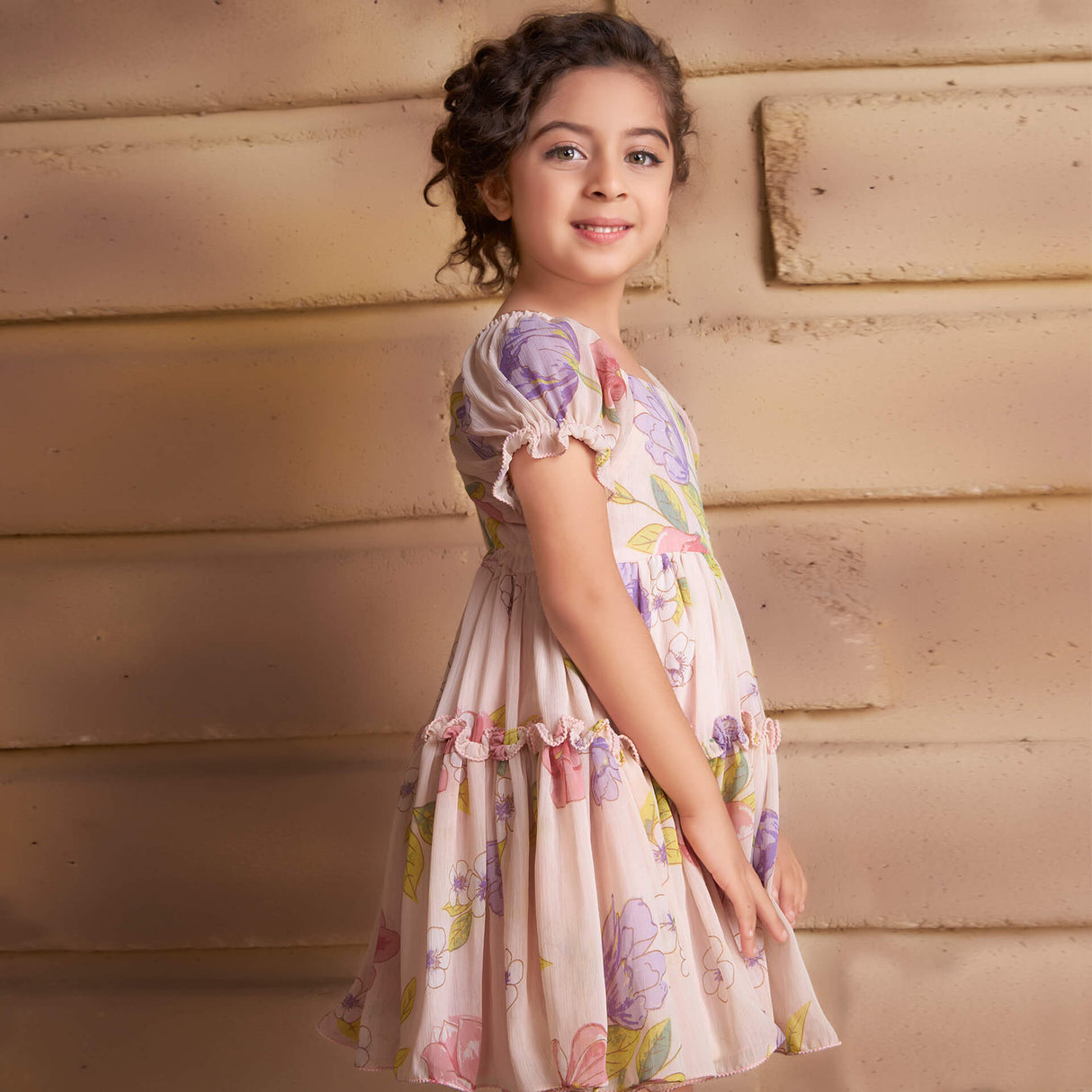 Side view of a girl dressed in a pink floral printed chiffon ruffle dress