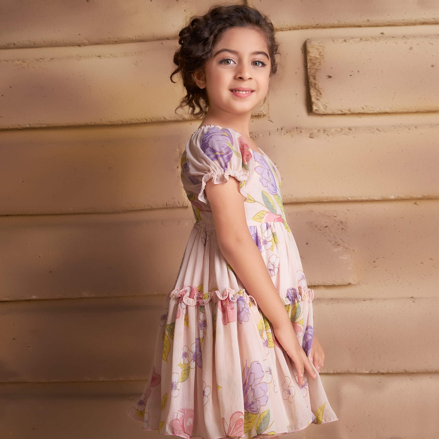Side view of a girl dressed in a pink floral printed chiffon ruffle dress