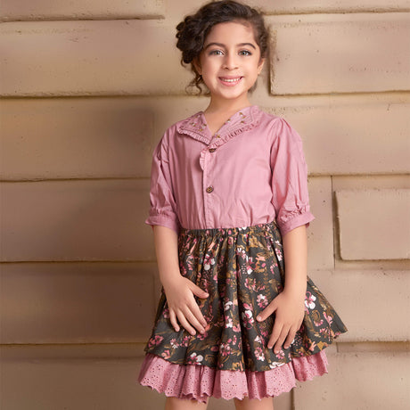 In a pink embroidered blouse and floral printed skirt, the girl smiles as she strikes a pose