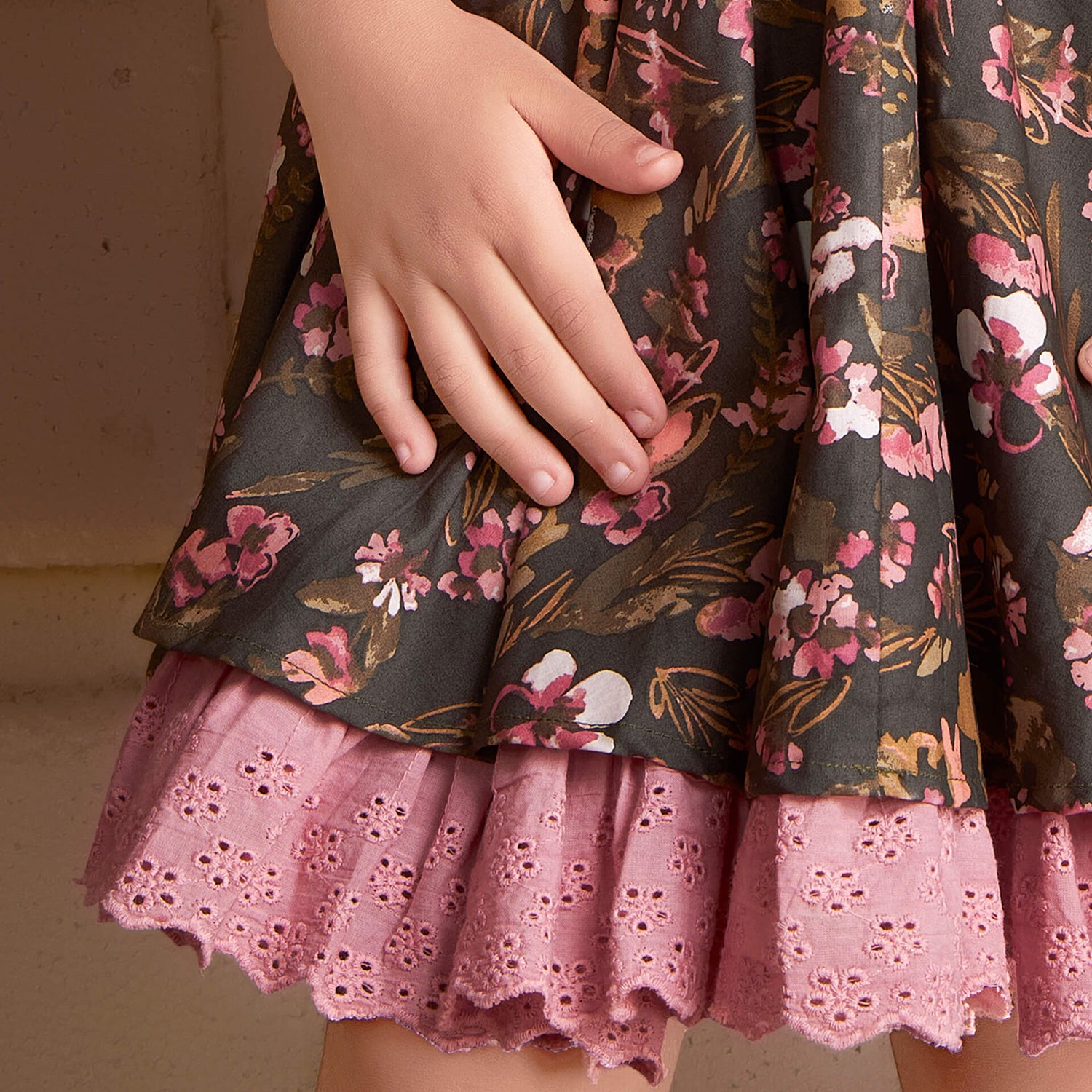 A detailed close-up of a green floral printed skirt paired with pink embroiderd blouse adorned with delicated lace