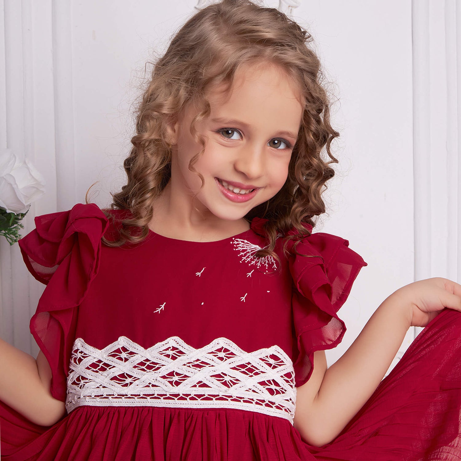 Close up of a girl in a red chiffon battenburg lace dress with pleated skirt