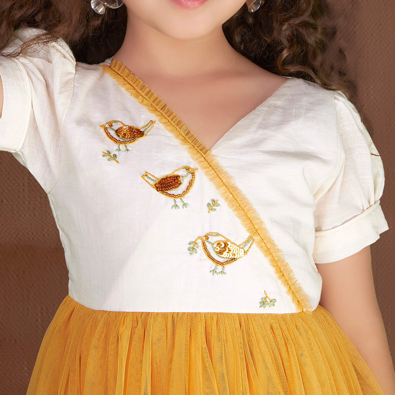 Detailed close-up of sequin bird embroidery embellishment on a yellow tulle dress.