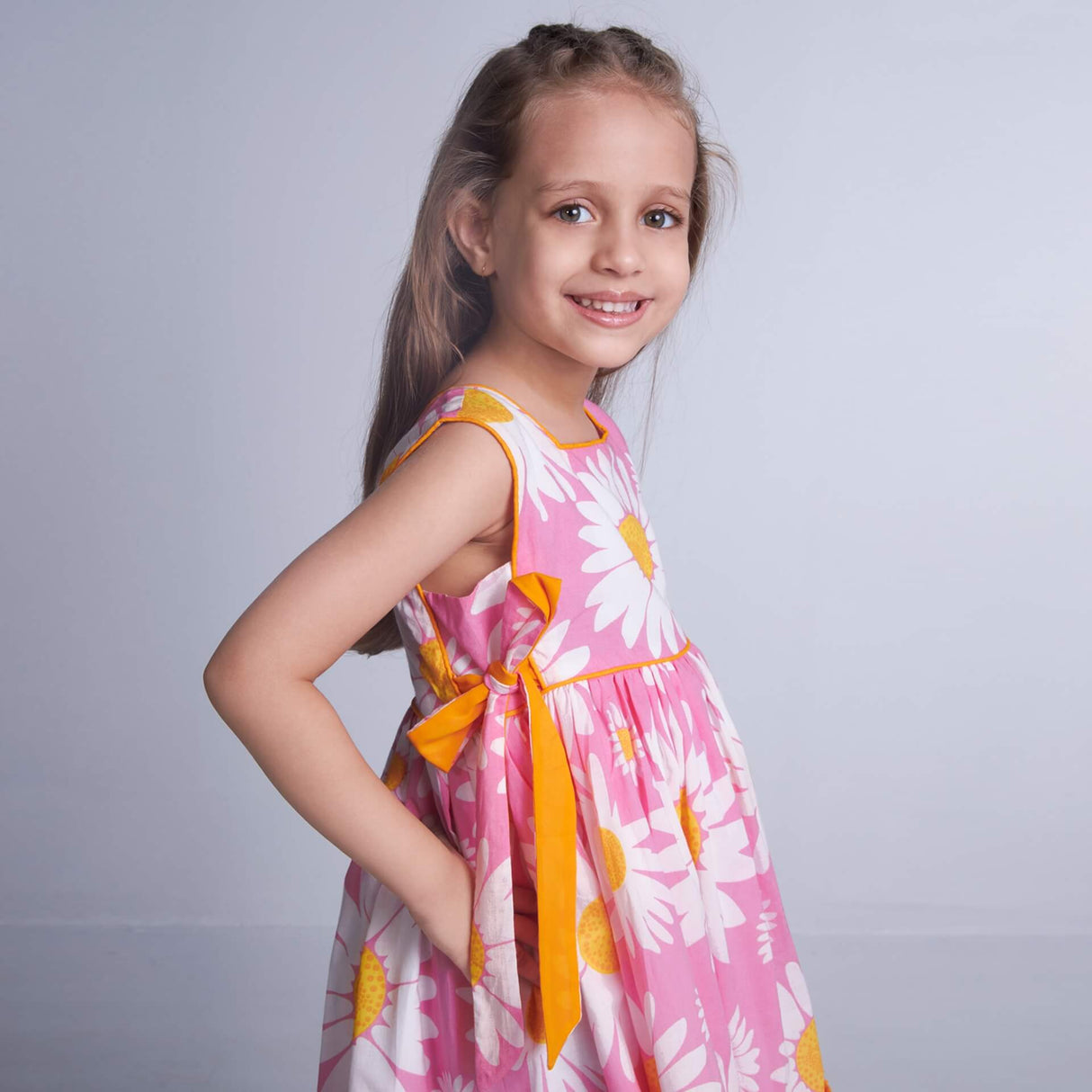 A girl in sleeveless pink floral dress with side ties