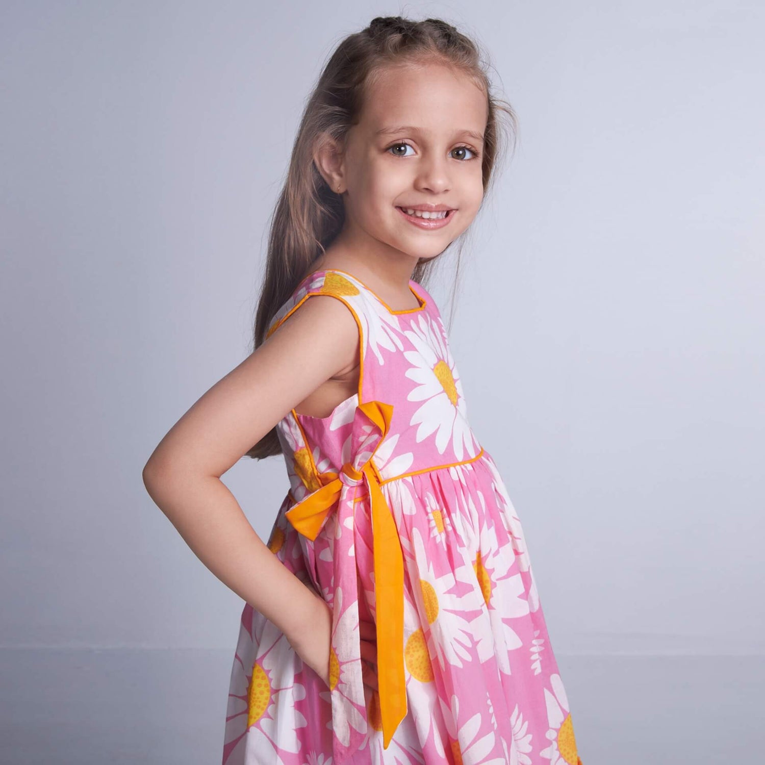 A girl in sleeveless pink floral dress with side ties