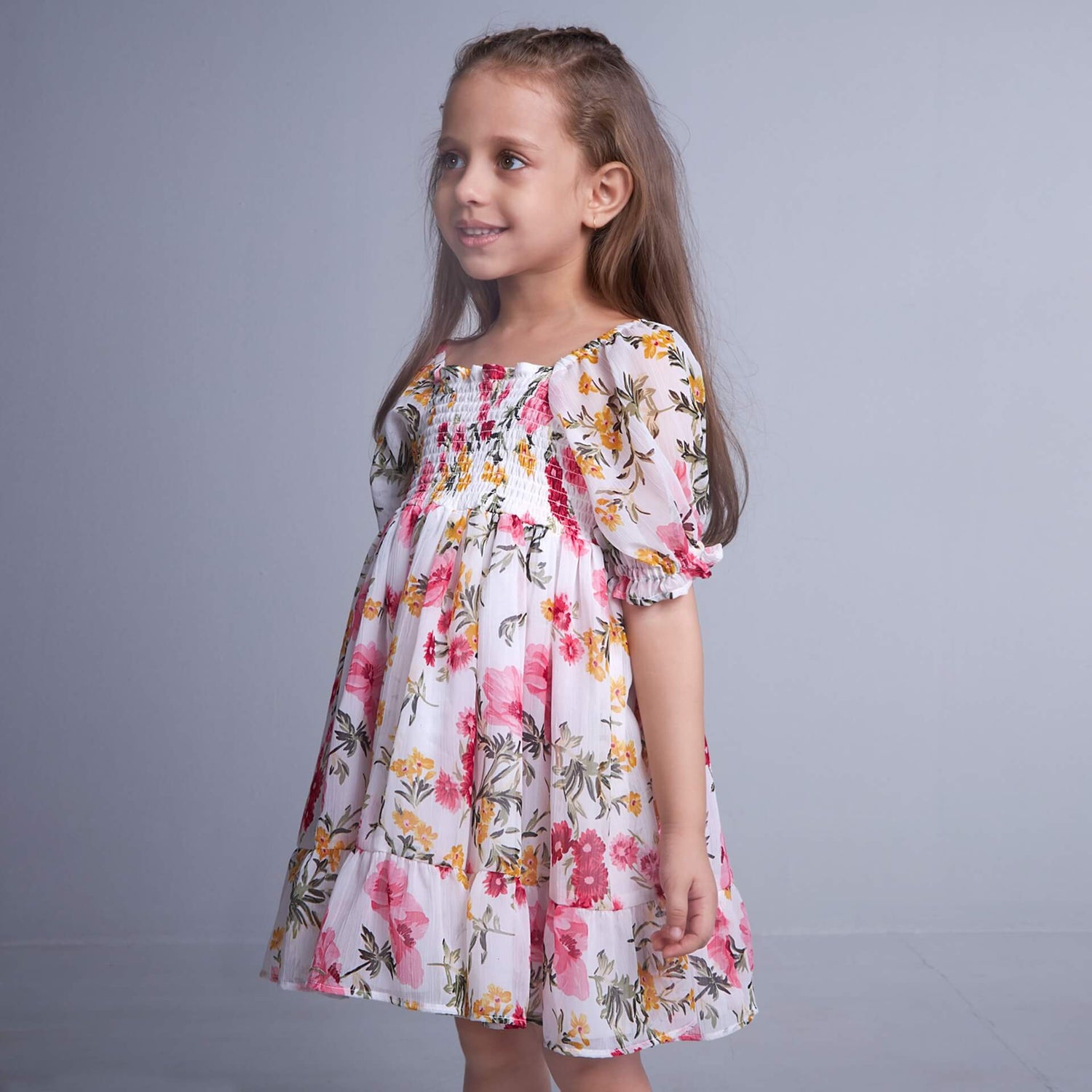 From the side, a girl dressed in white floral elasticated dress