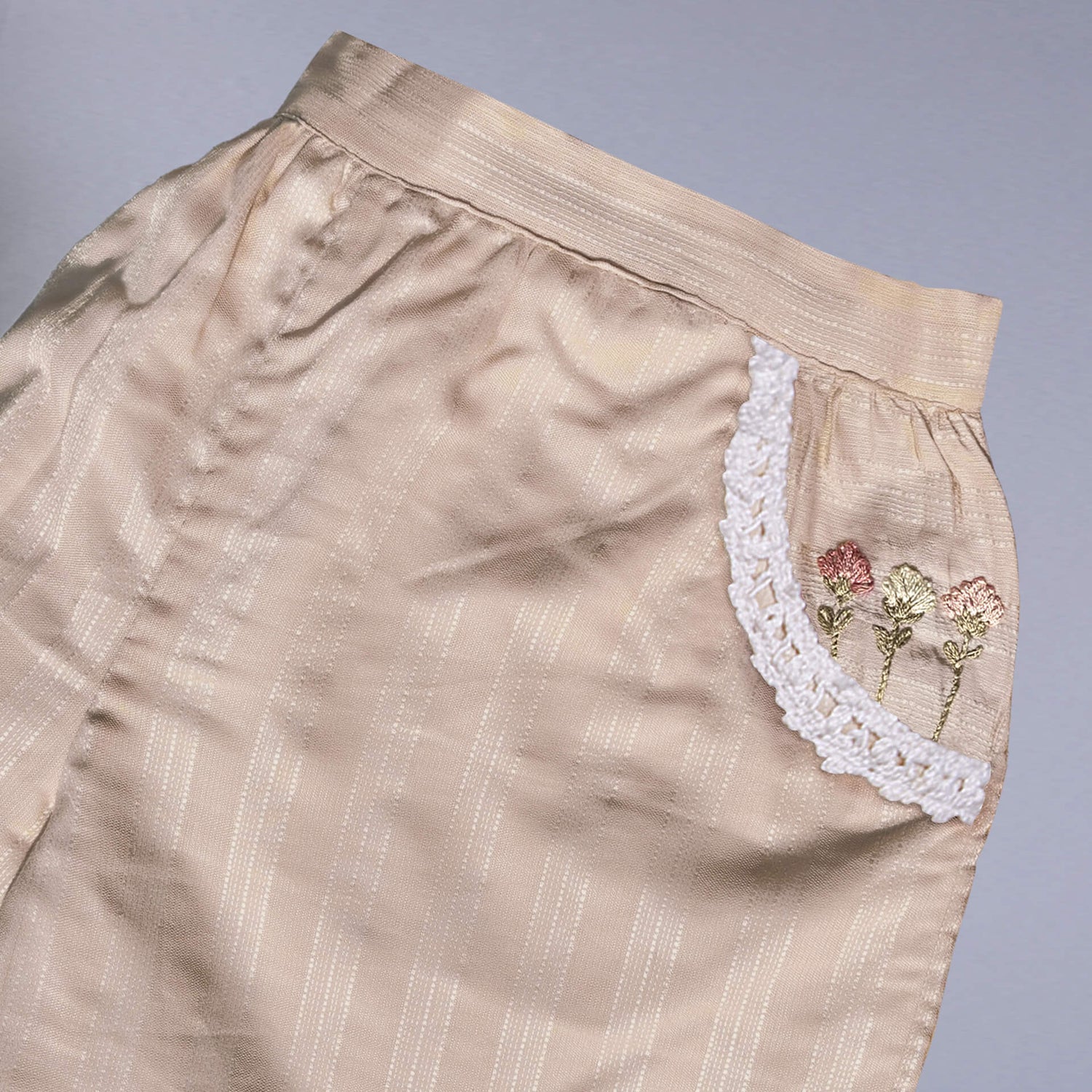 Flat lay of a tan hand embroidered shorts with dual side pockets and lace trims