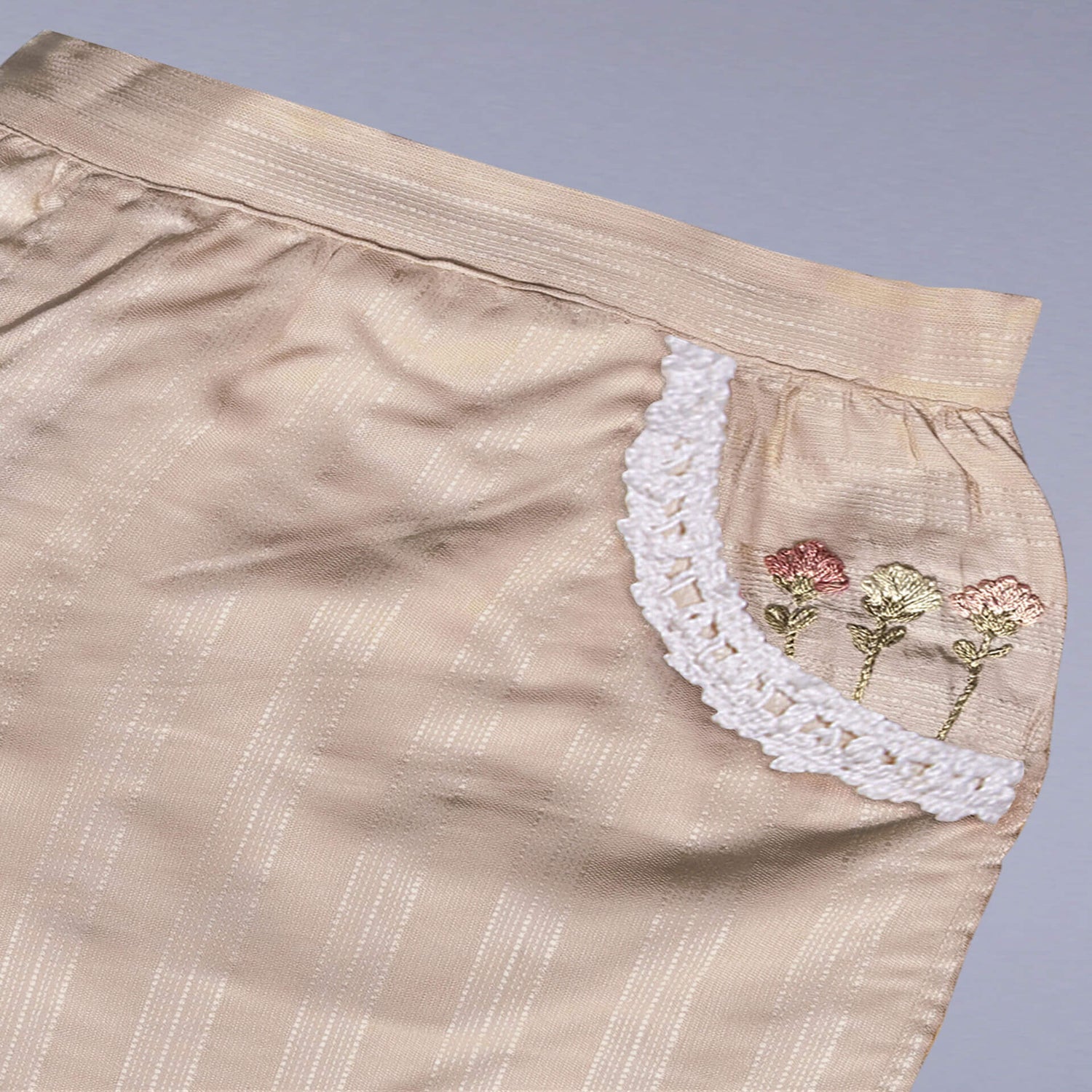 Flat lay of a tan hand embroidered shorts with dual side pockets and lace trims