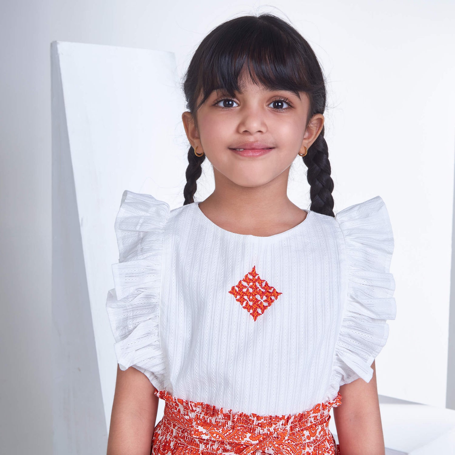 Closeup of a girl in ivory embroidered blouse and orange floral printed skirt